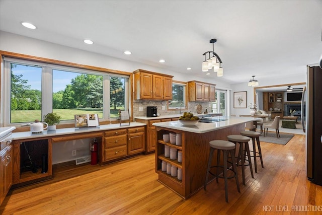 48W142 Milnamow Dr, Maple Park, IL 60151 - kitchen with light countertops, freestanding refrigerator, brown cabinetry, a kitchen breakfast bar, and light wood-style floors