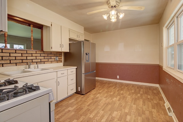 512 S Hebbard St, Joliet, IL 60433 - kitchen with white gas range, stainless steel fridge with ice dispenser, a sink, ceiling fan, and white cabinetry