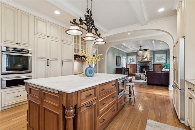 2423 Harrison St, Evanston, IL 60201 - kitchen with stainless steel appliances, arched walkways, light wood-type flooring, ceiling fan, and a stone fireplace