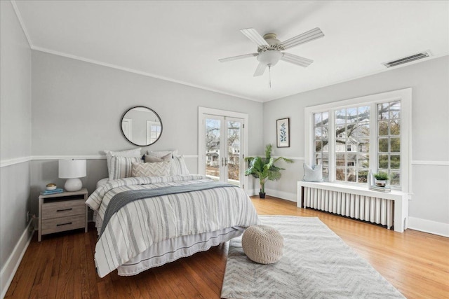 2423 Harrison St, Evanston, IL 60201 - bedroom featuring radiator heating unit, access to outside, baseboards, wood finished floors, and french doors
