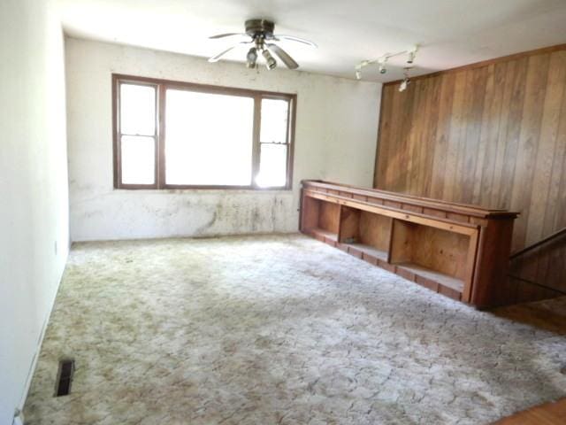 573 Moore St, Kankakee, IL 60901 - unfurnished living room featuring ceiling fan, wooden walls, and carpet floors