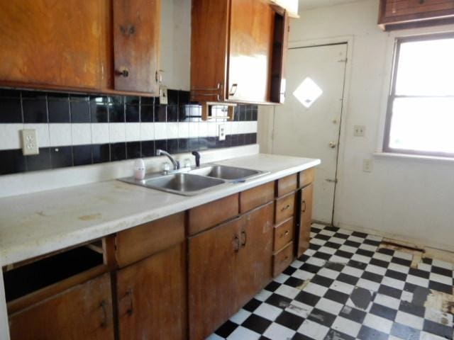 573 Moore St, Kankakee, IL 60901 - kitchen featuring a sink, light flooring, light countertops, tasteful backsplash, and brown cabinetry