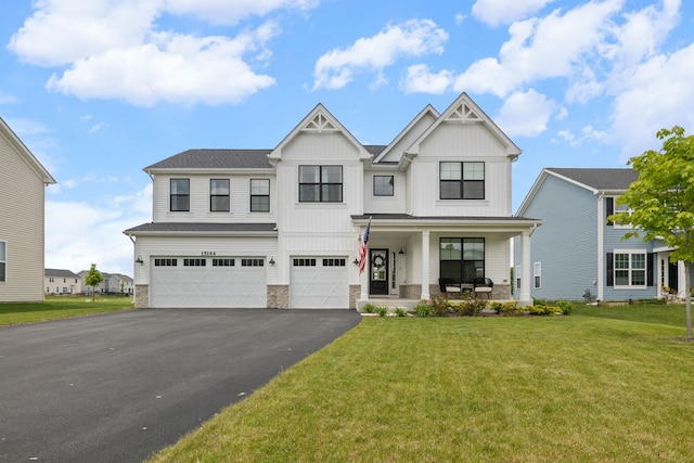 view of front of home featuring a porch, driveway, a garage, stone siding, and a front yard