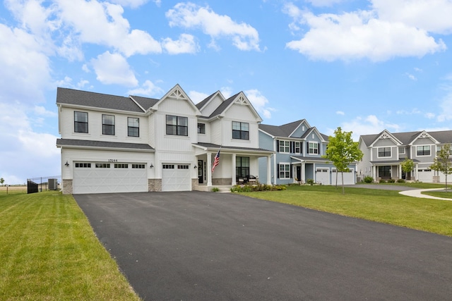 townhome / multi-family property featuring a residential view, stone siding, a garage, driveway, and a front lawn