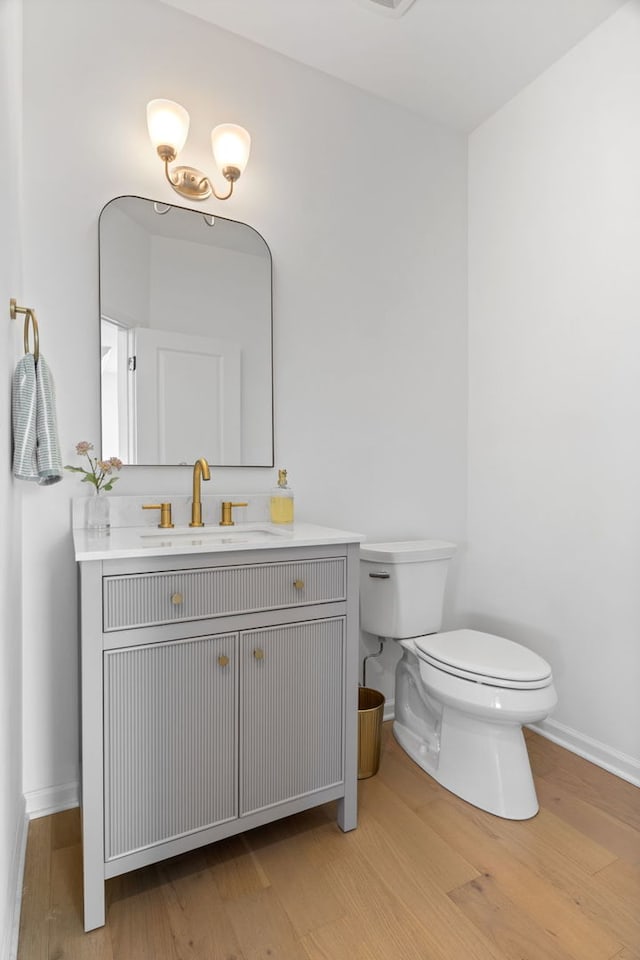 bathroom with wood finished floors, toilet, baseboards, and vanity