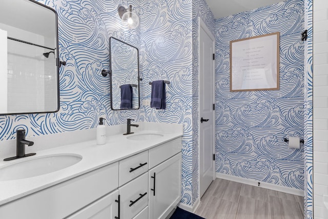 full bath featuring wallpapered walls, double vanity, and baseboards