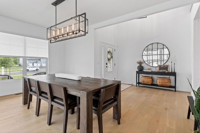 dining space featuring light wood-type flooring, a chandelier, and baseboards