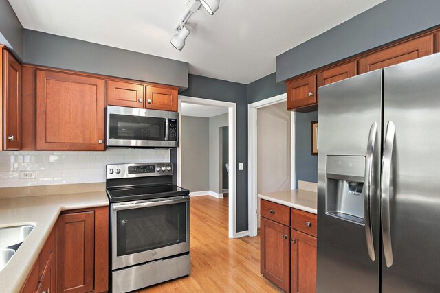 kitchen with stainless steel appliances, brown cabinets, and light countertops