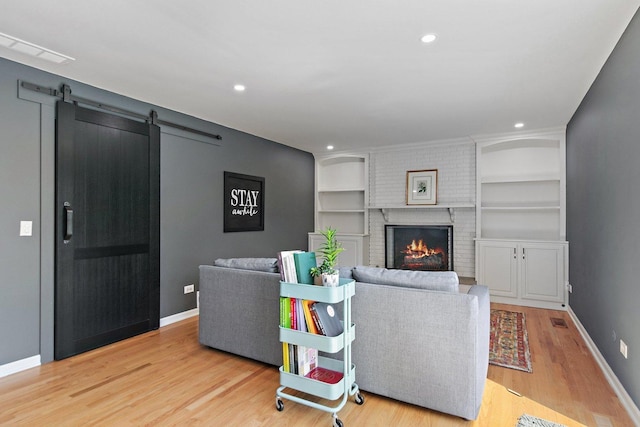 living area featuring wood finished floors, baseboards, a fireplace, built in features, and recessed lighting