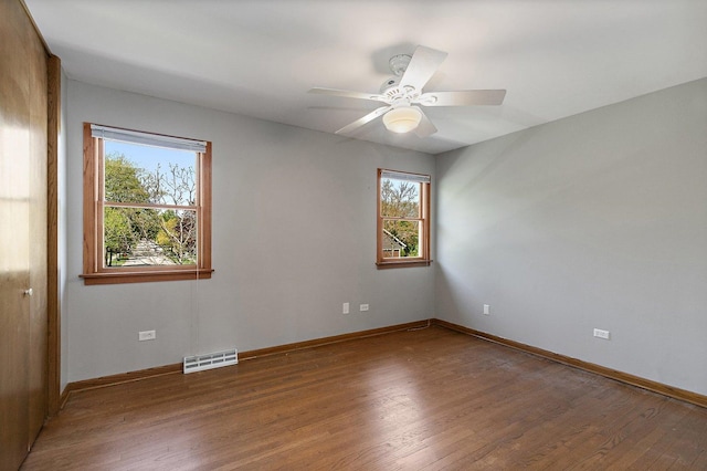 spare room featuring healthy amount of natural light, wood finished floors, and baseboards