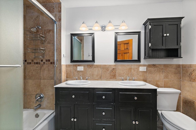 full bathroom with tile walls, shower / washtub combination, toilet, and double vanity