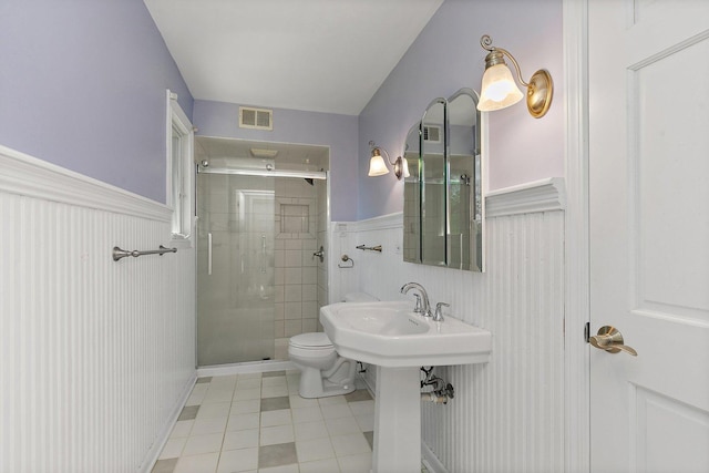 bathroom with tile patterned floors, a wainscoted wall, a shower stall, and toilet