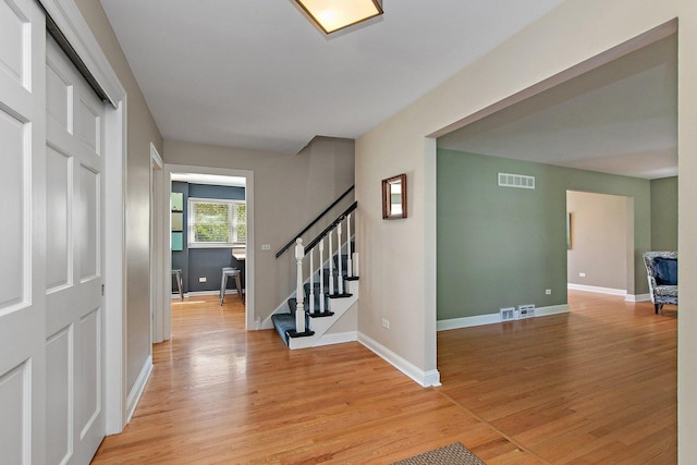 foyer entrance featuring light wood-style flooring, stairs, and baseboards