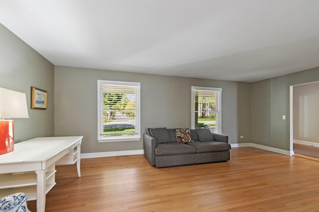 living room with light wood-type flooring, plenty of natural light, and baseboards