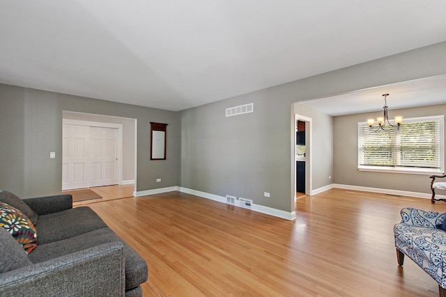 living room featuring a chandelier, light wood-style flooring, and baseboards