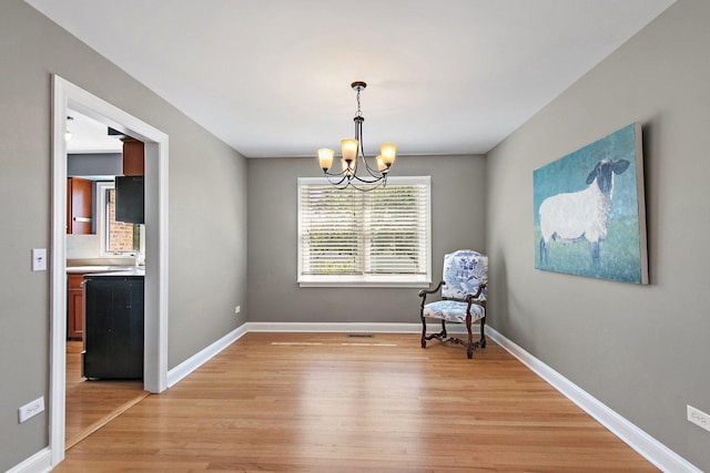 unfurnished room featuring light wood-style flooring, a chandelier, and baseboards