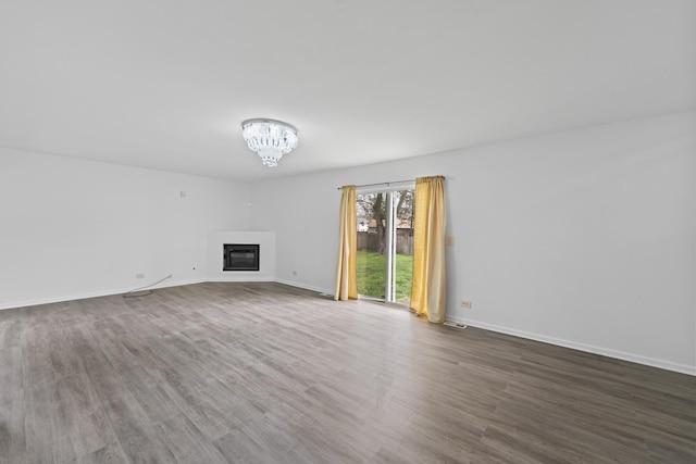 16215 S Trumbull Ave S, Markham, IL 60428 - unfurnished living room with wood finished floors, a glass covered fireplace, baseboards, and a chandelier