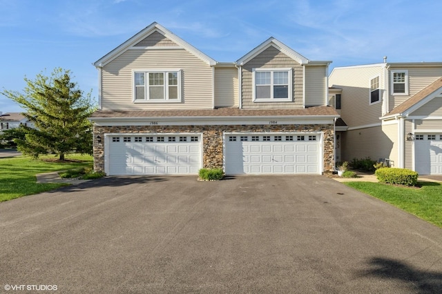 view of front facade with asphalt driveway, a garage, and stone siding