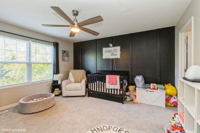 bedroom featuring a crib, carpet flooring, and a ceiling fan