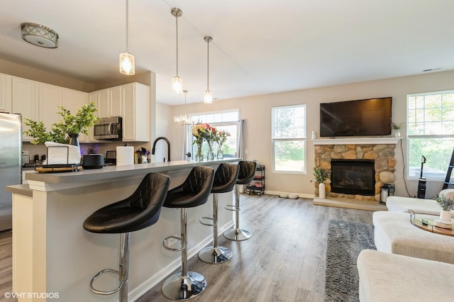 kitchen featuring stainless steel appliances, light wood-type flooring, open floor plan, a kitchen bar, and baseboards