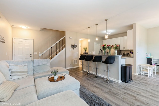living area featuring light wood-style floors, stairway, and baseboards