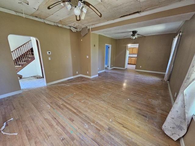 empty room with a ceiling fan, hardwood / wood-style flooring, baseboards, and arched walkways