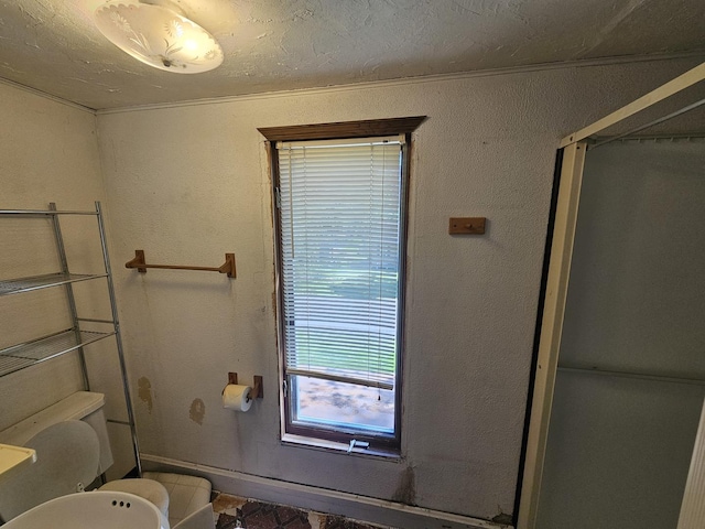 bathroom featuring baseboards, toilet, and a shower