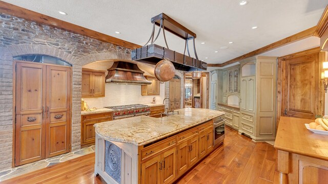 137 Singletree Rd, Orland Park, IL 60467 - kitchen featuring a sink, light wood finished floors, oven, custom range hood, and a kitchen island with sink
