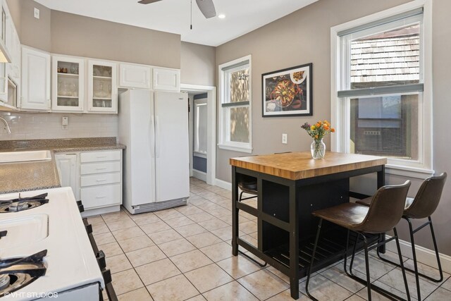 6329 N Hermitage Ave, Chicago, IL 60660 - kitchen with freestanding refrigerator, a sink, ceiling fan, white cabinets, and glass insert cabinets