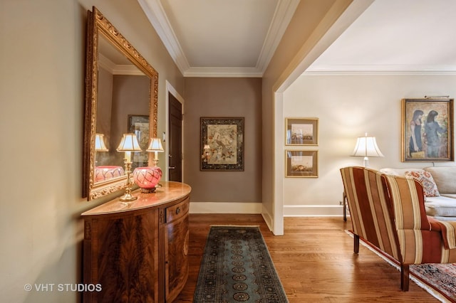 hall with wood finished floors, ornamental molding, and baseboards