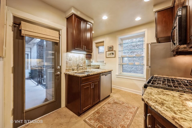 kitchen featuring stainless steel appliances, a sink, decorative backsplash, light stone counters, and recessed lighting