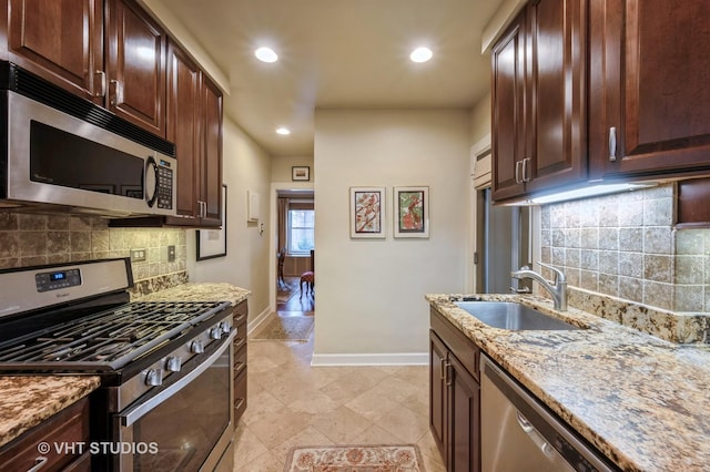 kitchen with appliances with stainless steel finishes, baseboards, a sink, light stone counters, and recessed lighting