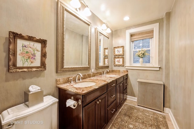 full bathroom with radiator heating unit, toilet, double vanity, baseboards, and tile patterned floors