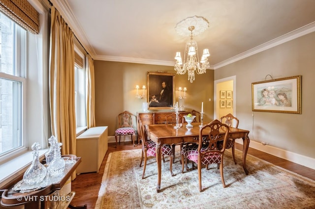 dining area featuring a chandelier, wood finished floors, crown molding, and baseboards