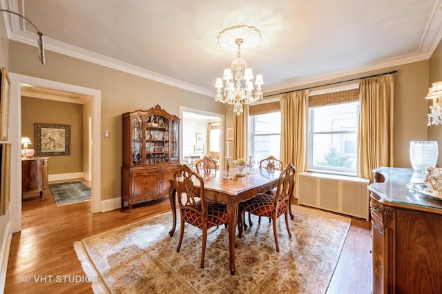 dining room with a chandelier, ornamental molding, light wood-type flooring, baseboards, and radiator