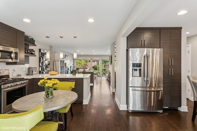2751 Prairie Ave, Evanston, IL 60201 - kitchen with appliances with stainless steel finishes, a peninsula, recessed lighting, dark brown cabinets, and dark wood finished floors