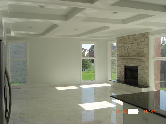 unfurnished living room with coffered ceiling, a fireplace, and beam ceiling