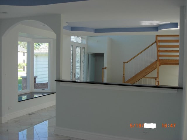 kitchen with baseboards, arched walkways, marble finish flooring, and dark countertops