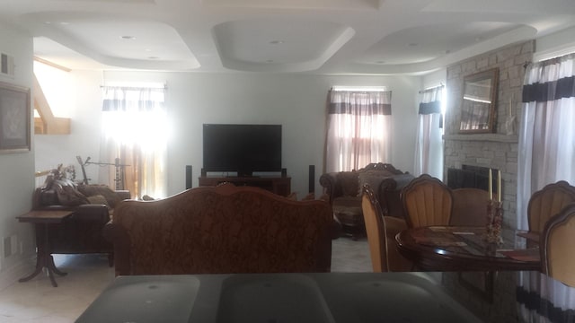 living room featuring coffered ceiling and a stone fireplace