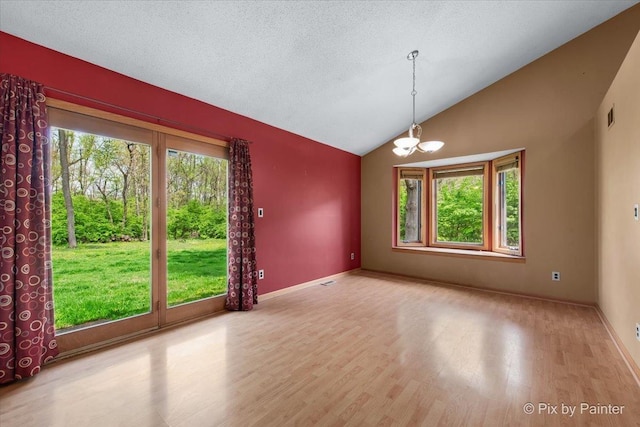 118 Centralia Pl, Poplar Grove, IL 61065 - empty room featuring plenty of natural light, vaulted ceiling, wood finished floors, and a chandelier