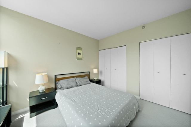 carpeted bedroom featuring multiple closets and baseboards