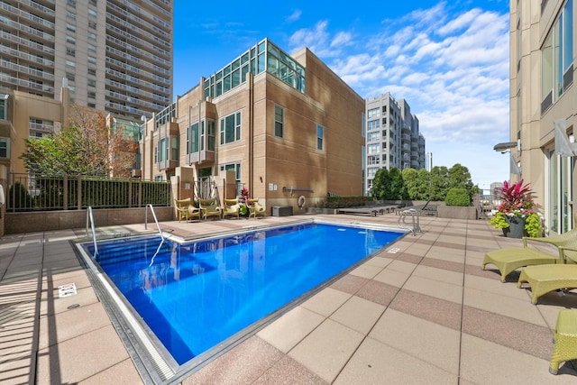 community pool with a patio area and fence
