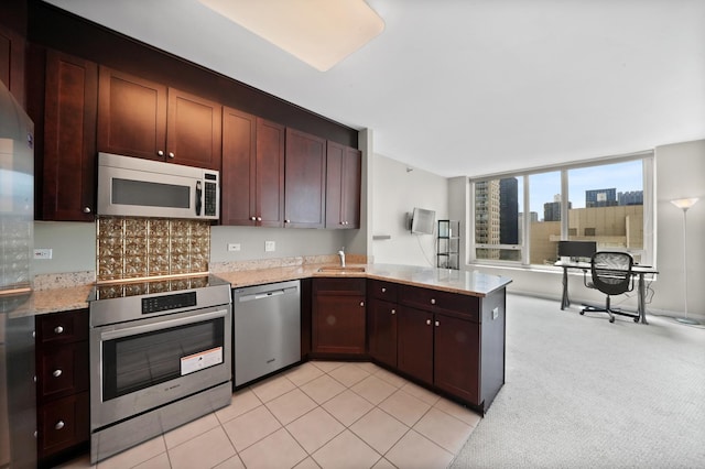 kitchen with dishwasher, white microwave, wall oven, a sink, and a peninsula
