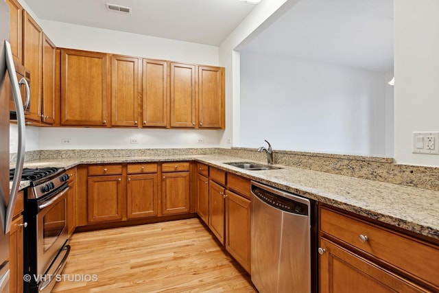 4727 N Clark St Unit 2S, Chicago, IL 60640 - kitchen with appliances with stainless steel finishes, brown cabinets, light stone countertops, and light wood-style flooring
