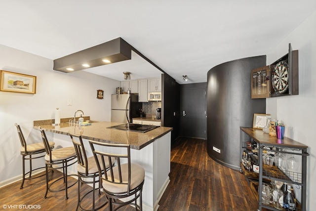 kitchen with stainless steel appliances, dark wood-style floors, a peninsula, a kitchen breakfast bar, and recessed lighting