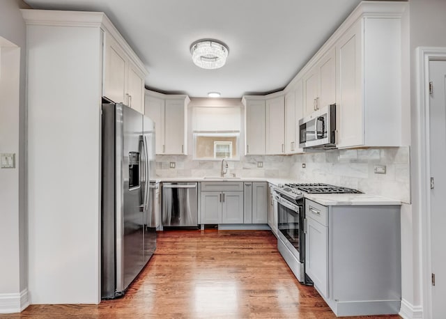 11311 S Stewart Ave, Chicago, IL 60628 - kitchen featuring stainless steel appliances, light wood-type flooring, backsplash, and light countertops