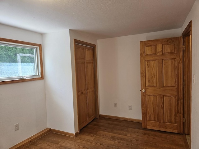 unfurnished bedroom featuring dark wood finished floors, baseboards, and a closet