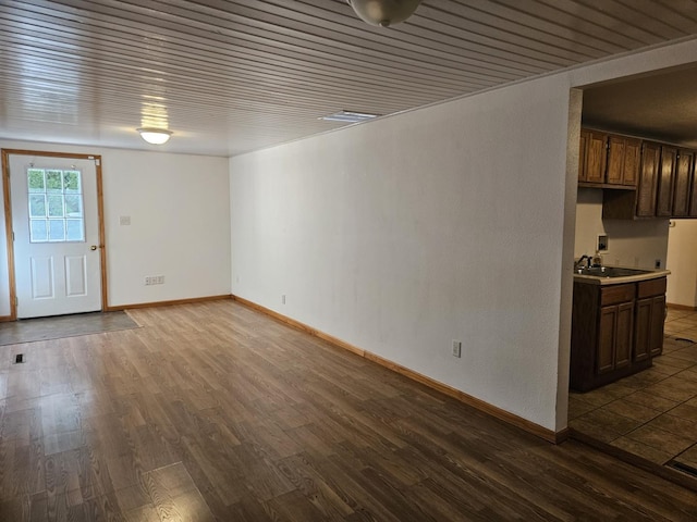 unfurnished living room featuring a sink, dark wood-style flooring, and baseboards