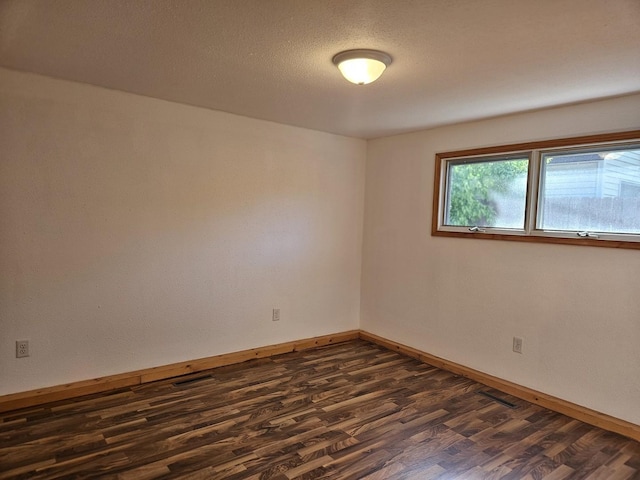 unfurnished room featuring dark wood-type flooring and baseboards