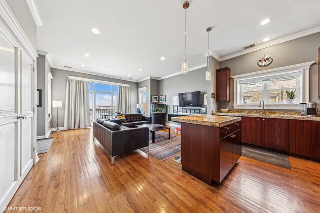 2451 S Western Ave Unit 3N, Chicago, IL 60608 - kitchen featuring light wood finished floors, a kitchen island, crown molding, open floor plan, and pendant lighting